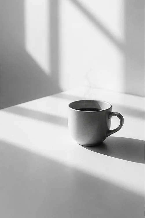 昼下がり、壁に落ちる窓の光とコーヒー